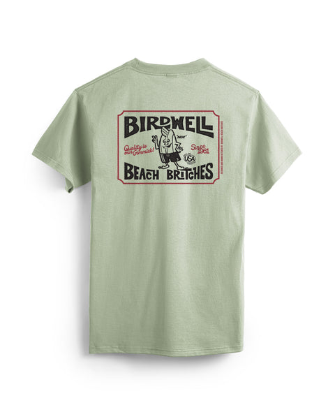 Desert green, garment-dyed cotton Hangtag T-Shirt with short sleeves and a large vintage-style Birdwell Beach Britches graphic on the back featuring a cartoon character in swimwear and stylized design elements.