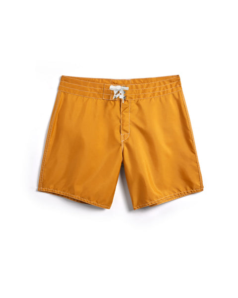 A pair of gold 310 Boardshorts from Birdwell featuring a white drawstring, laid flat on a white background.