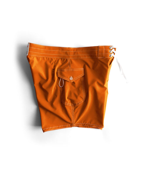 The 806 SurfStretch Side Pocket Boardshorts in medium orange feature white stitching, a back pocket with a button flap, metal key loop, and a white lace-up closure on the right side. Shown laid flat on a white background.