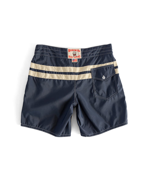 The 300 Comp Stripe - Navy/Bone boardshorts feature beige stripes across the back, a right-side button-flap pocket, a red and white waistband label, and are proudly made in the USA.