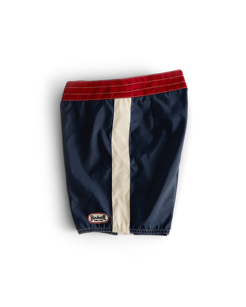 The 300 Legend - Navy/Red/Bone dog jacket features a red waistband, navy body, and cream stripe in boardshort style, finished with a Blackwell patch near the hem and shown on a white background.
